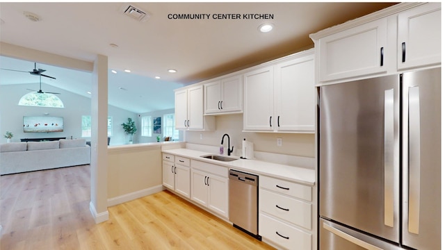 kitchen with appliances with stainless steel finishes, vaulted ceiling, white cabinets, ceiling fan, and sink