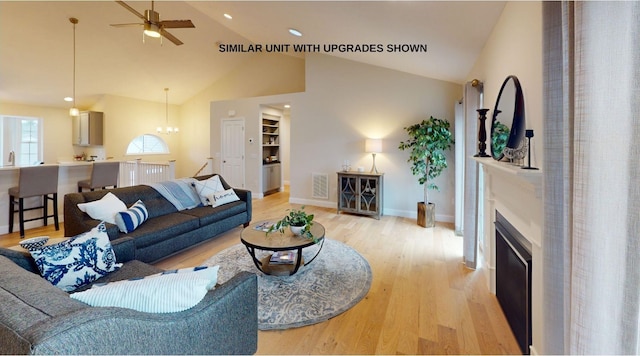 living room with ceiling fan with notable chandelier, light hardwood / wood-style floors, and high vaulted ceiling