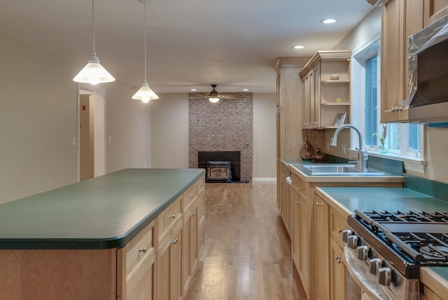 kitchen with a stone fireplace, stainless steel appliances, a center island, ceiling fan, and sink