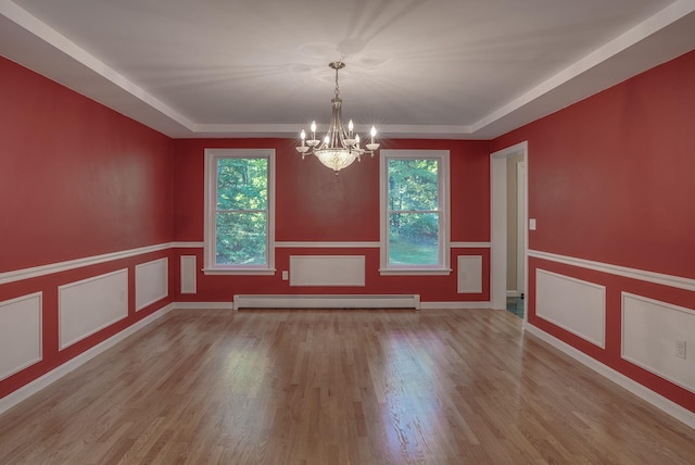 empty room featuring light hardwood / wood-style flooring, a baseboard heating unit, and a wealth of natural light