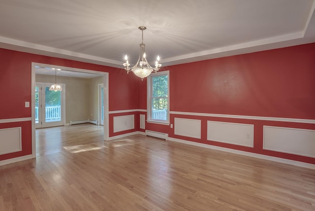 empty room featuring a baseboard radiator, a wealth of natural light, and a chandelier