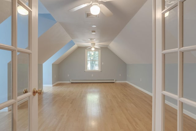 additional living space with a baseboard heating unit, lofted ceiling, ceiling fan, and light hardwood / wood-style floors