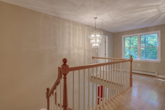 corridor featuring hardwood / wood-style flooring, a chandelier, and a baseboard heating unit