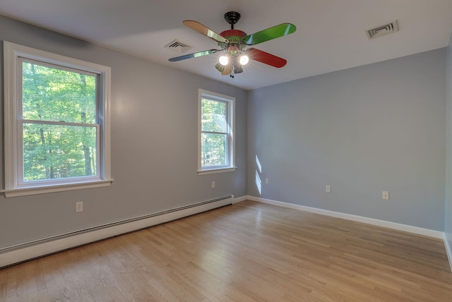 spare room with light wood-type flooring, a healthy amount of sunlight, ceiling fan, and a baseboard radiator