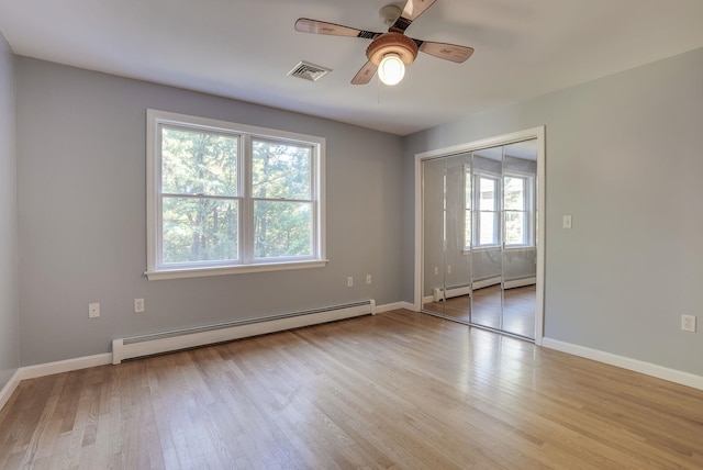 unfurnished room with a baseboard heating unit, ceiling fan, plenty of natural light, and light wood-type flooring