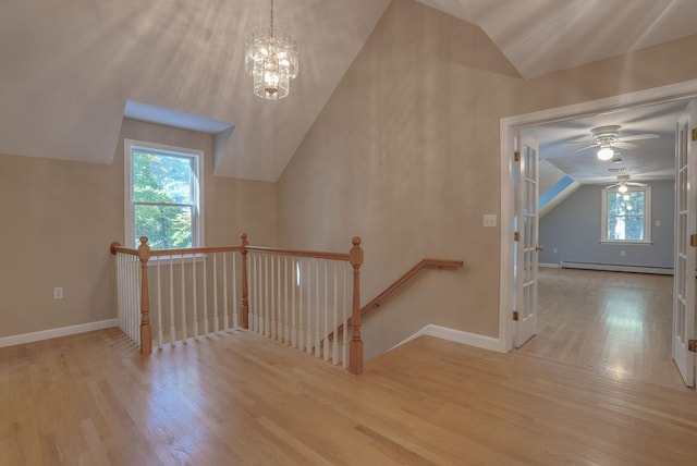 interior space featuring ceiling fan with notable chandelier, lofted ceiling, wood-type flooring, and a baseboard radiator