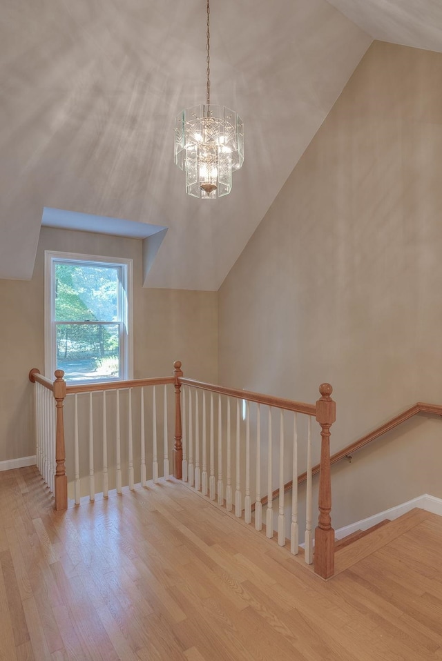 stairway featuring hardwood / wood-style flooring, a chandelier, and vaulted ceiling