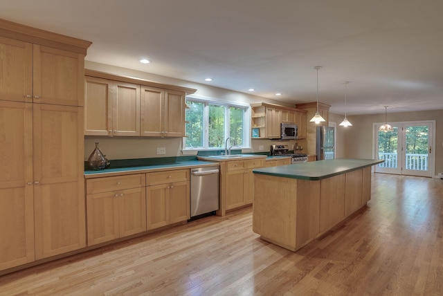 kitchen featuring light hardwood / wood-style flooring, appliances with stainless steel finishes, hanging light fixtures, and a kitchen island