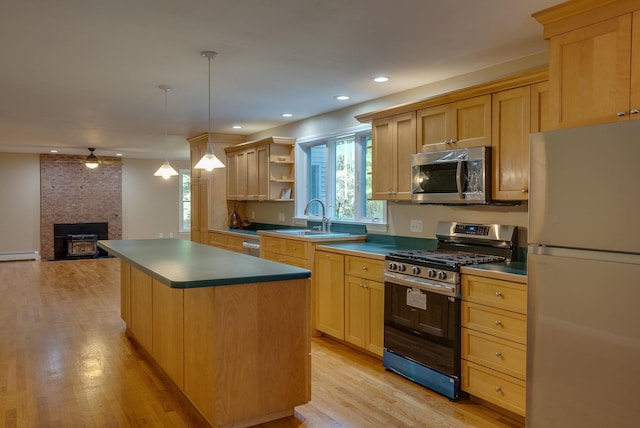 kitchen featuring light hardwood / wood-style floors, a fireplace, a kitchen island, stainless steel appliances, and sink