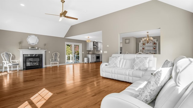 living room with ceiling fan with notable chandelier, lofted ceiling, and hardwood / wood-style floors