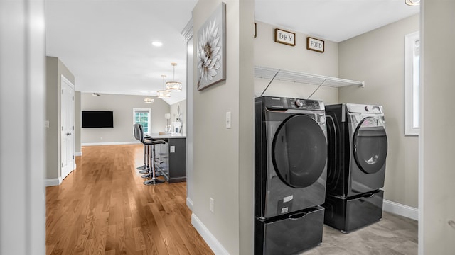 laundry room featuring separate washer and dryer, an inviting chandelier, and hardwood / wood-style floors