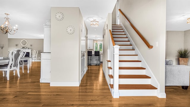 stairway with a notable chandelier and hardwood / wood-style floors