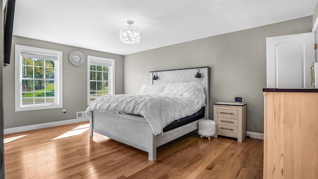 bedroom featuring an inviting chandelier and wood-type flooring