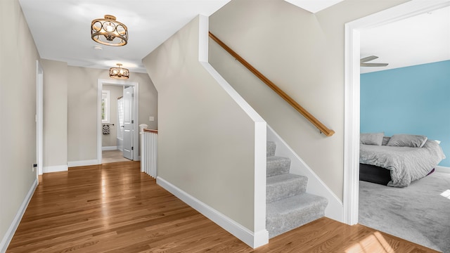 stairway with hardwood / wood-style floors and ceiling fan