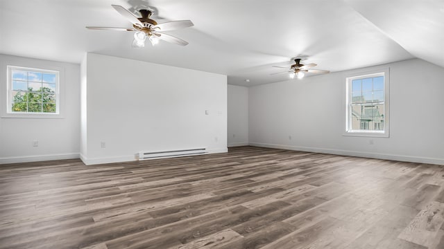 spare room featuring dark hardwood / wood-style floors, vaulted ceiling, baseboard heating, and ceiling fan