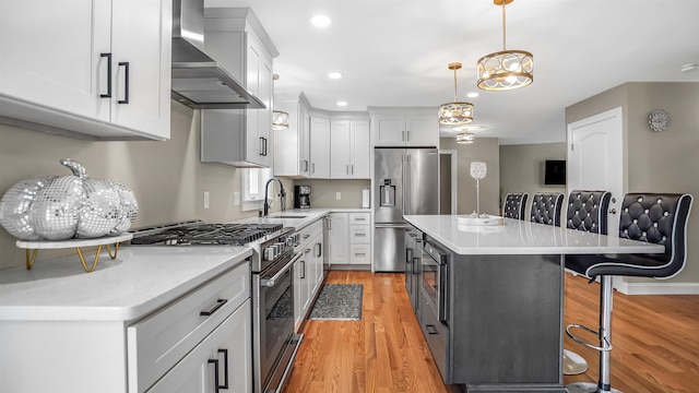 kitchen with a kitchen bar, a kitchen island, premium appliances, wall chimney exhaust hood, and decorative light fixtures