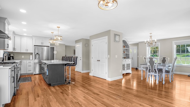 kitchen featuring a center island, light hardwood / wood-style floors, appliances with stainless steel finishes, and decorative light fixtures