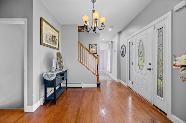 foyer with a notable chandelier, baseboard heating, and hardwood / wood-style floors