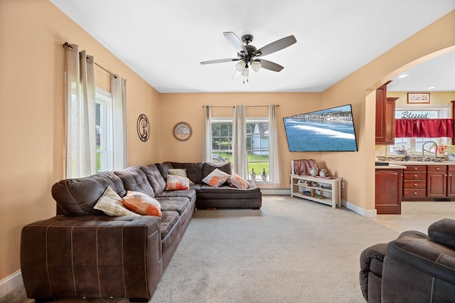 carpeted living room with ceiling fan and sink