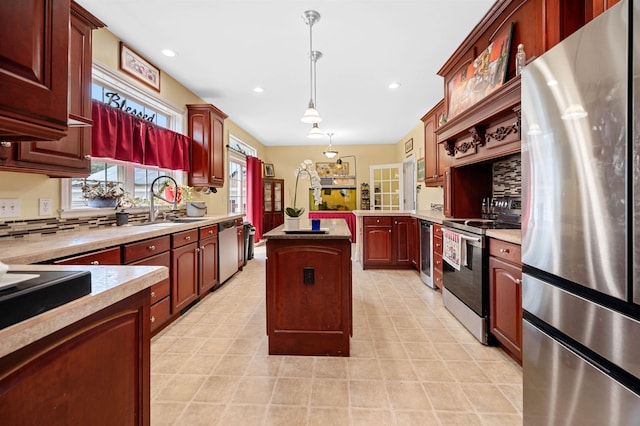 kitchen featuring pendant lighting, sink, a kitchen island, decorative backsplash, and stainless steel appliances