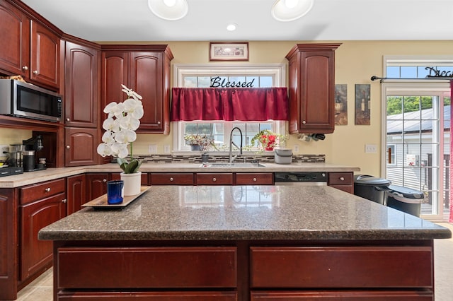 kitchen with light stone countertops, appliances with stainless steel finishes, sink, and a center island