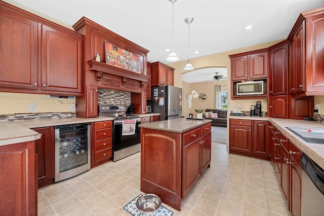 kitchen featuring ceiling fan, hanging light fixtures, sink, beverage cooler, and appliances with stainless steel finishes