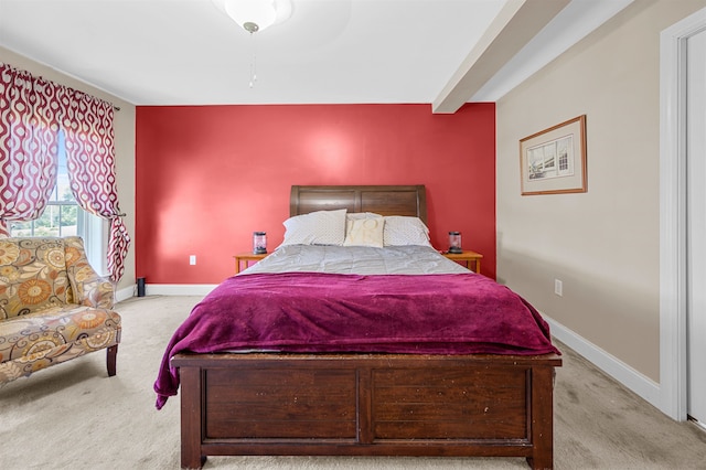 bedroom with light colored carpet and beamed ceiling