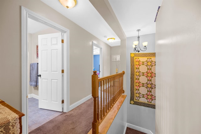 hallway with light colored carpet and a chandelier