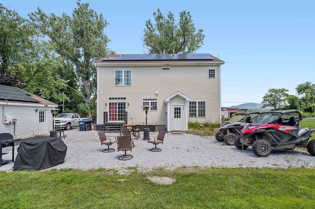 back of property featuring a patio area, solar panels, and a yard