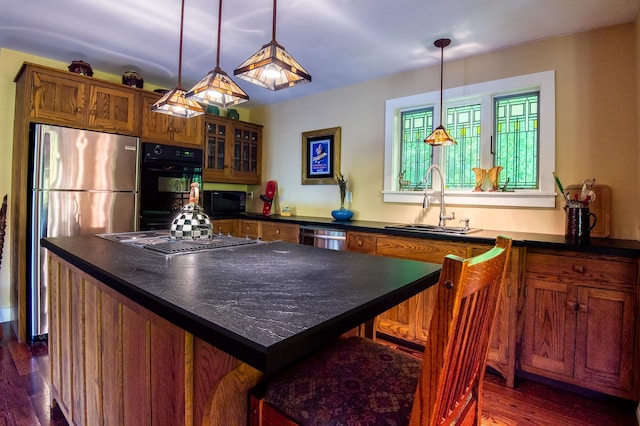 kitchen with sink, a kitchen island, hanging light fixtures, and black appliances