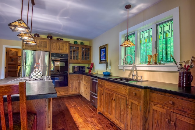 kitchen featuring black appliances, decorative light fixtures, dark hardwood / wood-style flooring, and sink