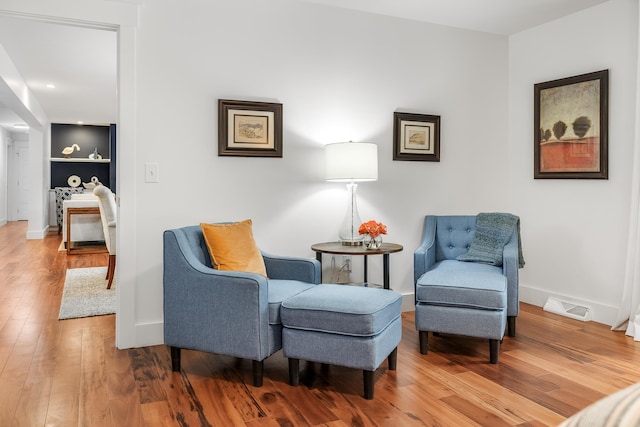 living area with built in features and hardwood / wood-style flooring