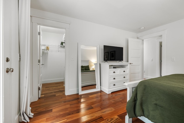 bedroom featuring a closet, dark wood-type flooring, and a walk in closet