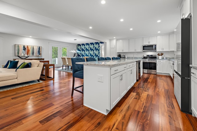 kitchen featuring stainless steel appliances, white cabinetry, a center island, and dark hardwood / wood-style flooring