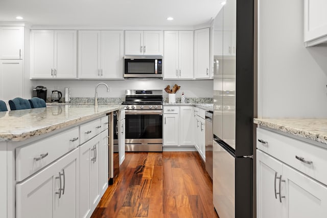 kitchen with stainless steel appliances, white cabinetry, and dark wood-type flooring