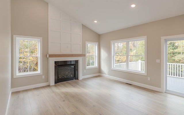 unfurnished living room with a fireplace, high vaulted ceiling, and light hardwood / wood-style flooring