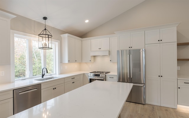 kitchen featuring vaulted ceiling, appliances with stainless steel finishes, white cabinetry, sink, and light hardwood / wood-style floors