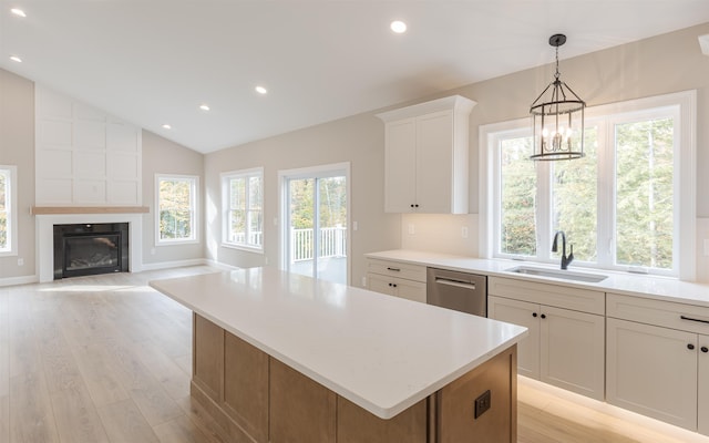 kitchen featuring lofted ceiling, sink, dishwasher, a kitchen island, and white cabinets