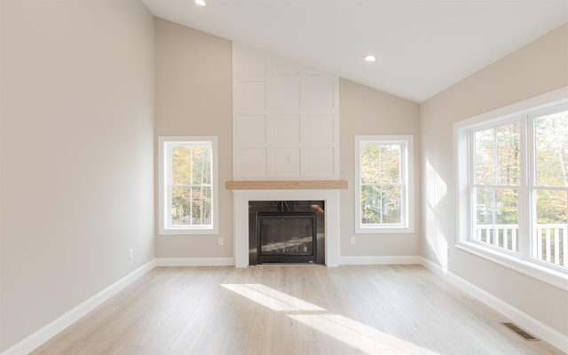 unfurnished living room featuring a fireplace, vaulted ceiling, and light wood-type flooring