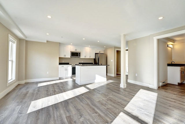 kitchen featuring stainless steel appliances, white cabinetry, light wood-type flooring, and a center island