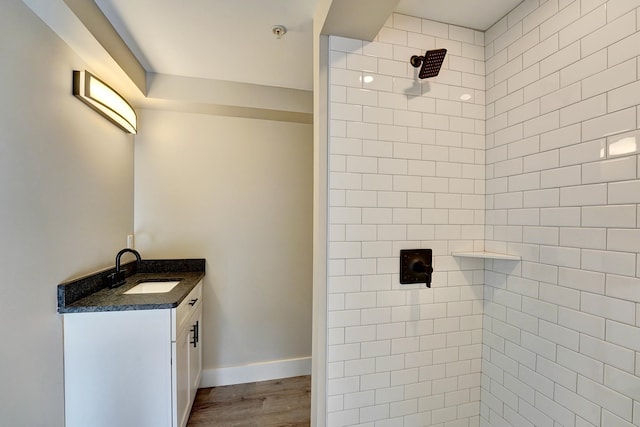 bathroom with tiled shower, vanity, and wood-type flooring