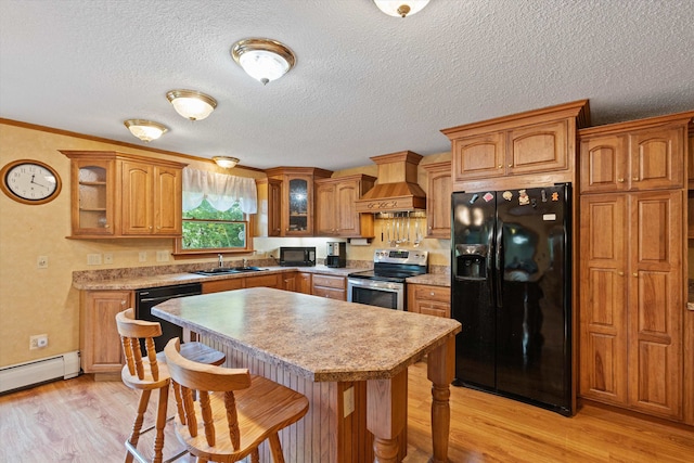 kitchen with custom range hood, light wood-type flooring, black appliances, ornamental molding, and sink