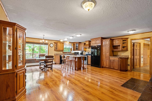 kitchen featuring premium range hood, a textured ceiling, light wood-type flooring, and black appliances