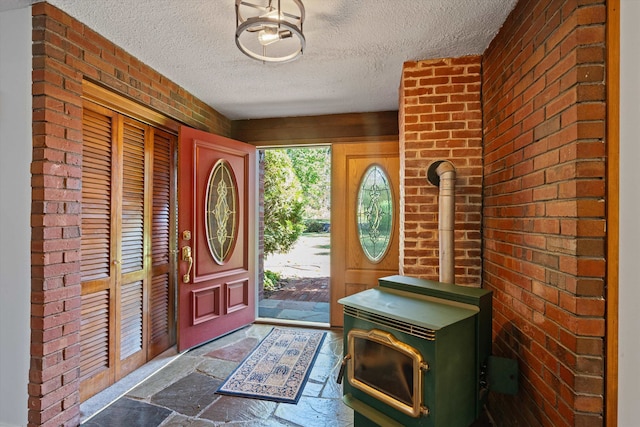 entryway with a textured ceiling, a wood stove, and brick wall