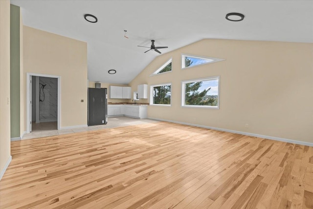 unfurnished living room with light hardwood / wood-style flooring, vaulted ceiling, ceiling fan, and sink