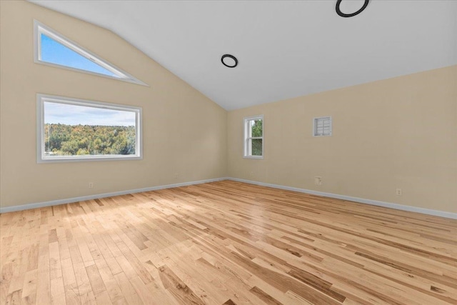 unfurnished room featuring light wood-type flooring, vaulted ceiling, and a wealth of natural light