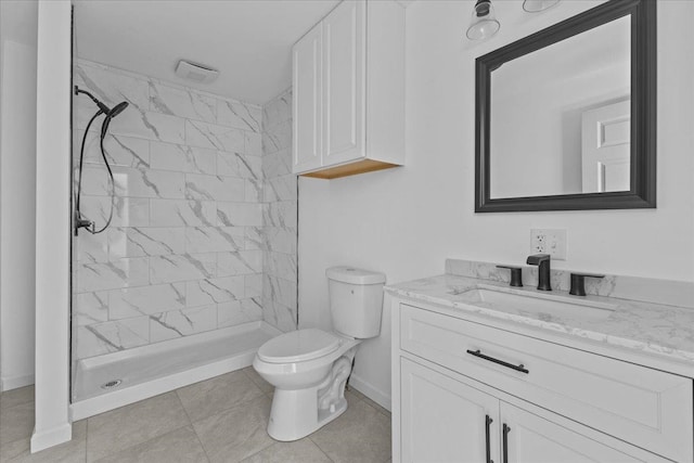 bathroom with vanity, tile patterned flooring, toilet, and tiled shower