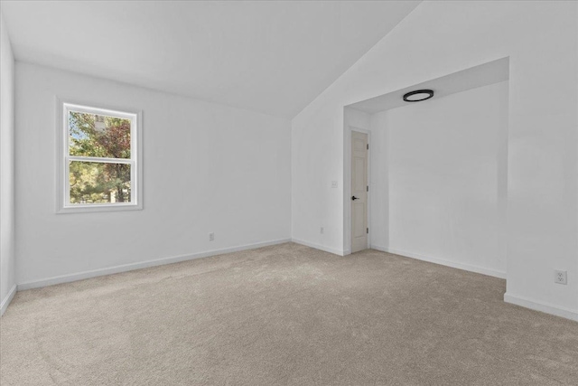 carpeted spare room featuring vaulted ceiling