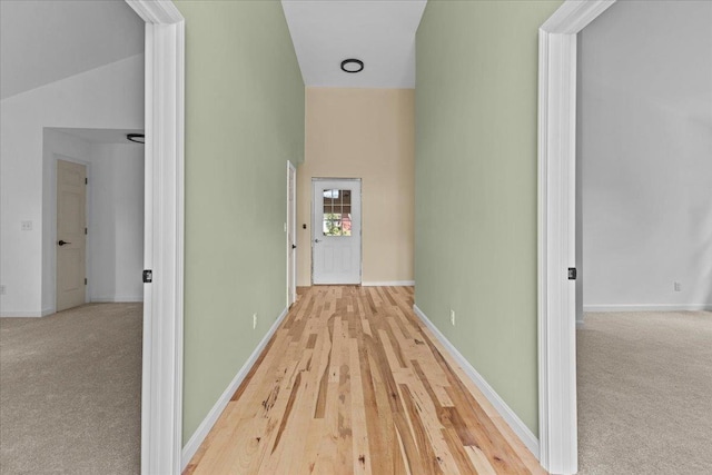 hall with light wood-type flooring and vaulted ceiling