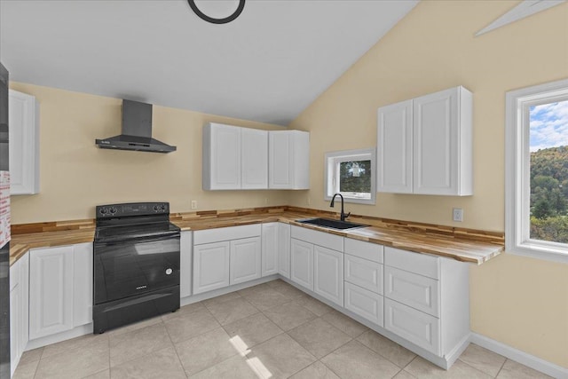 kitchen with black / electric stove, sink, wall chimney range hood, and butcher block counters